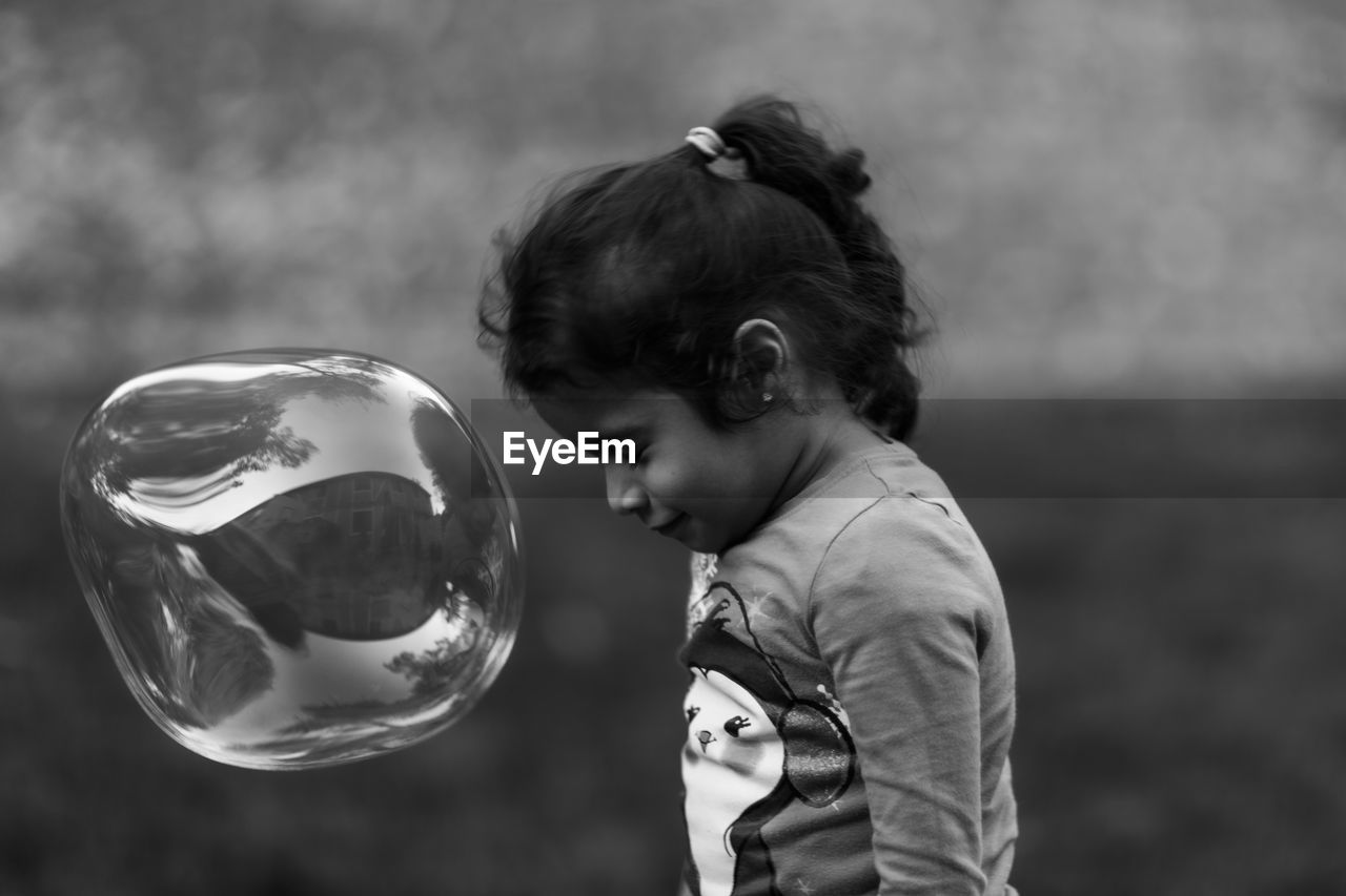 Side view of girl playing with bubble