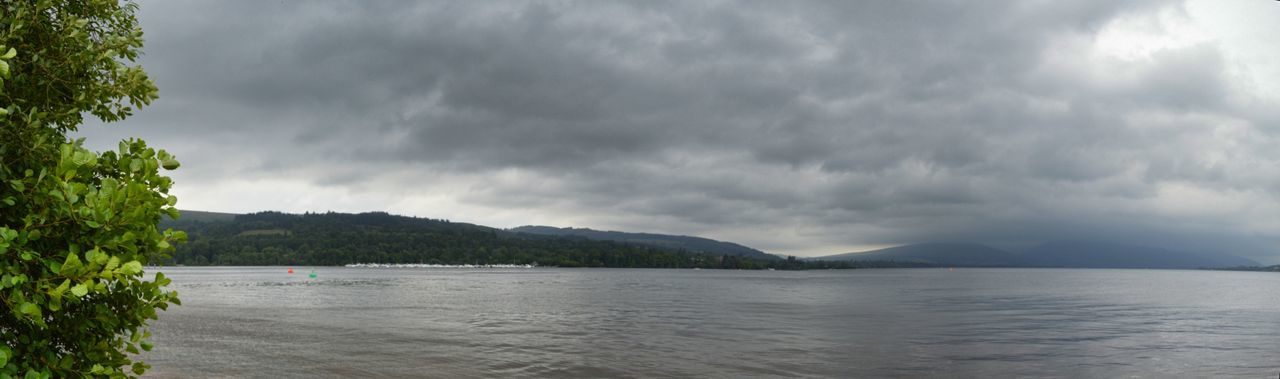 SCENIC VIEW OF SEA AND MOUNTAINS AGAINST STORM CLOUDS