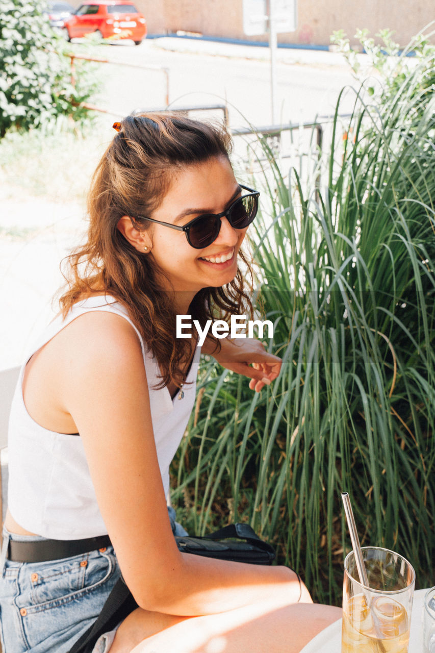 Side view of smiling young woman sitting outdoors