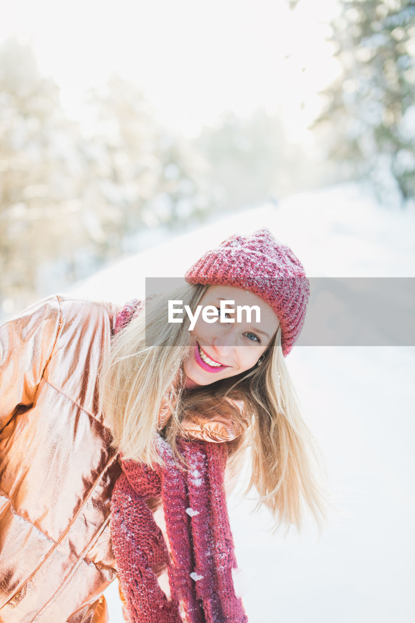 Portrait of smiling woman in warm clothing standing on snow