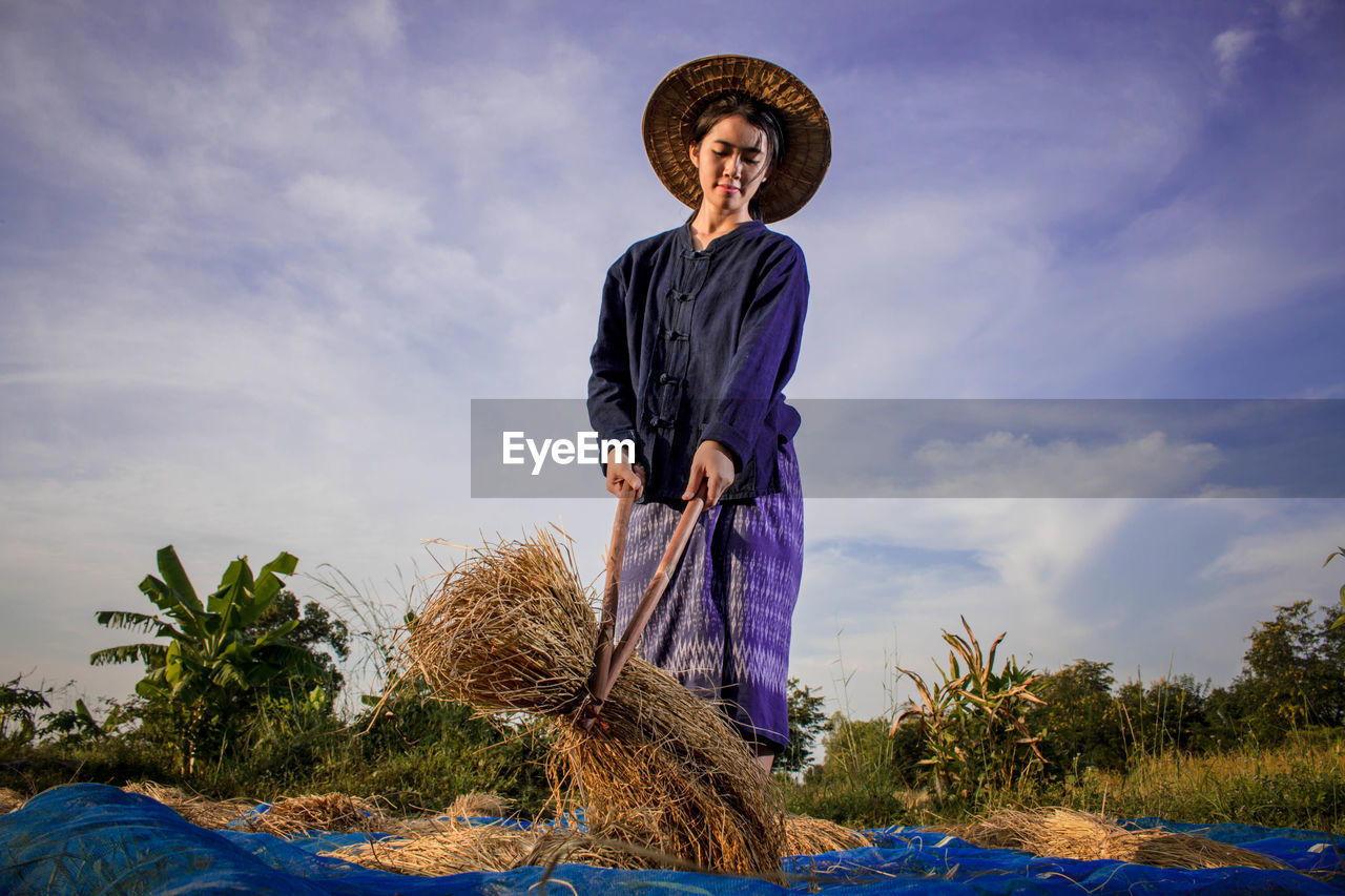 Low angle view of woman standing on field against sky