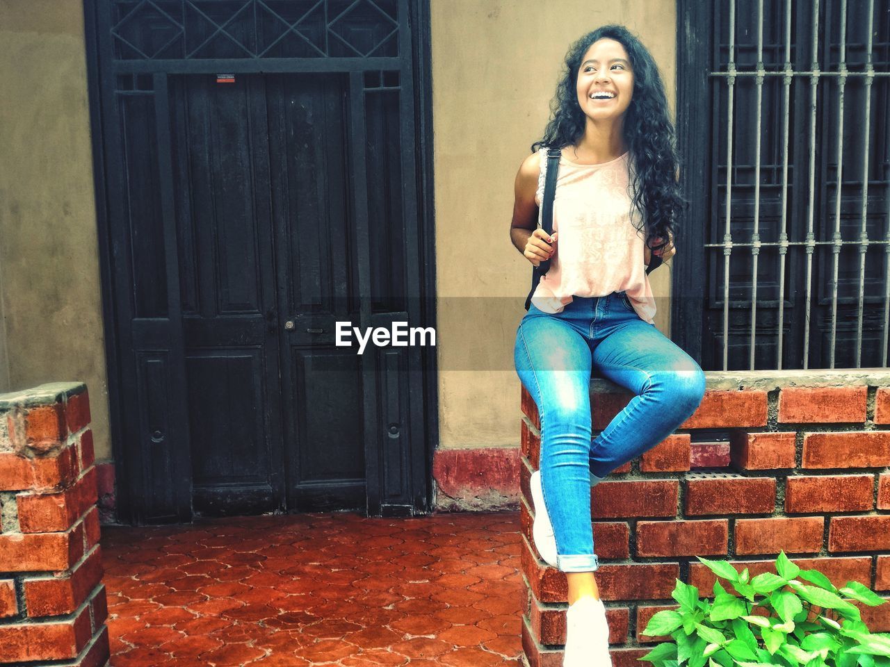 PORTRAIT OF YOUNG WOMAN SITTING ON DOOR