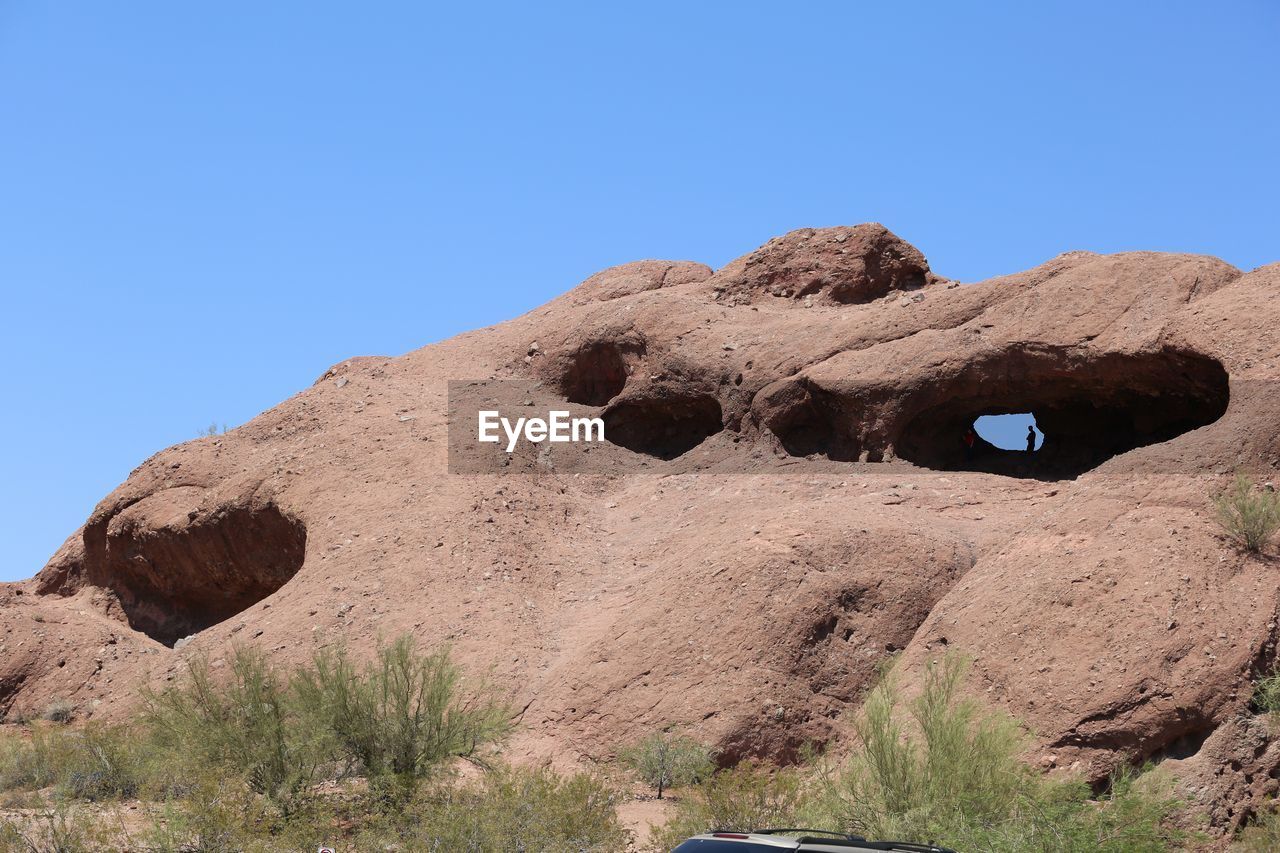 LOW ANGLE VIEW OF ROCK FORMATION AGAINST CLEAR BLUE SKY
