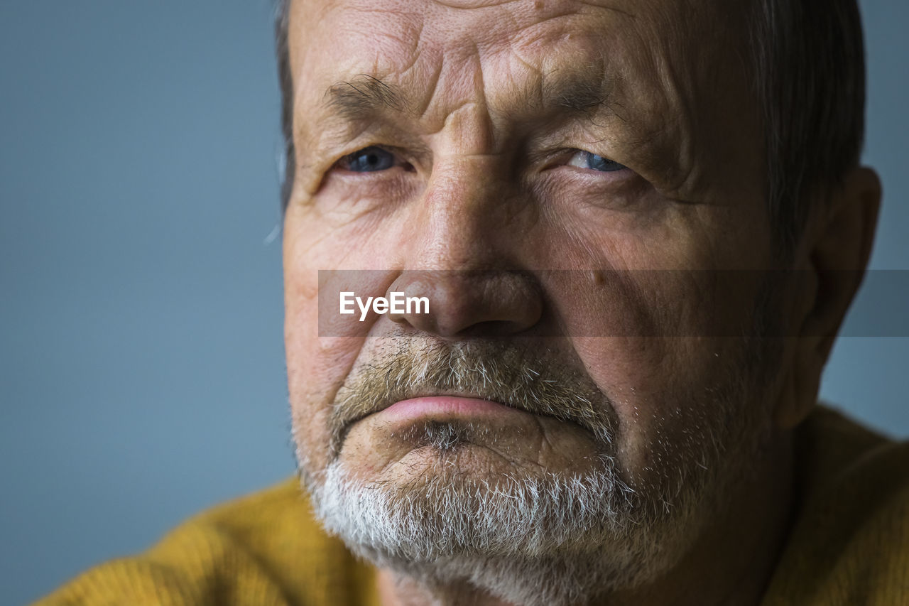 Close-up of senior man against blue background