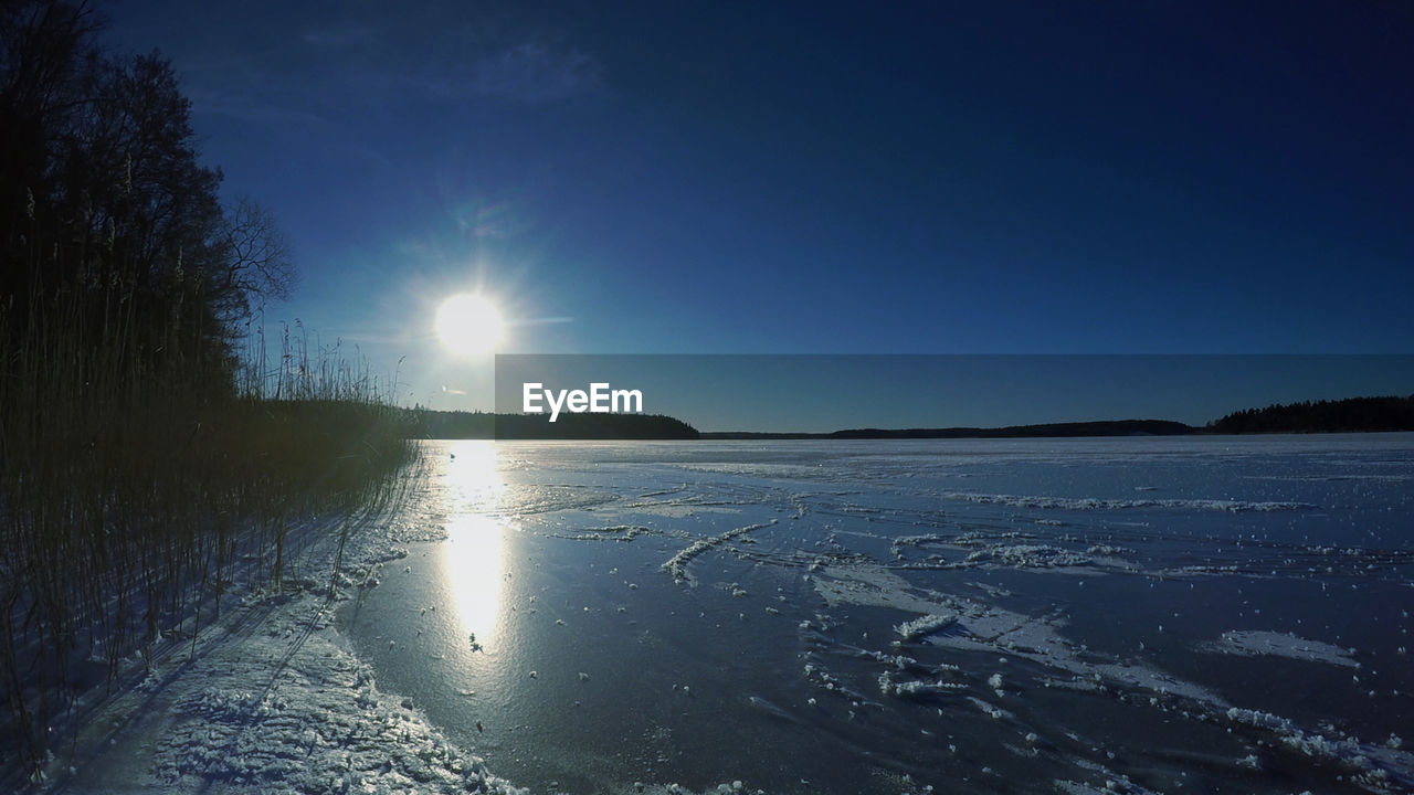 Scenic view of frozen lake against sky during sunny day