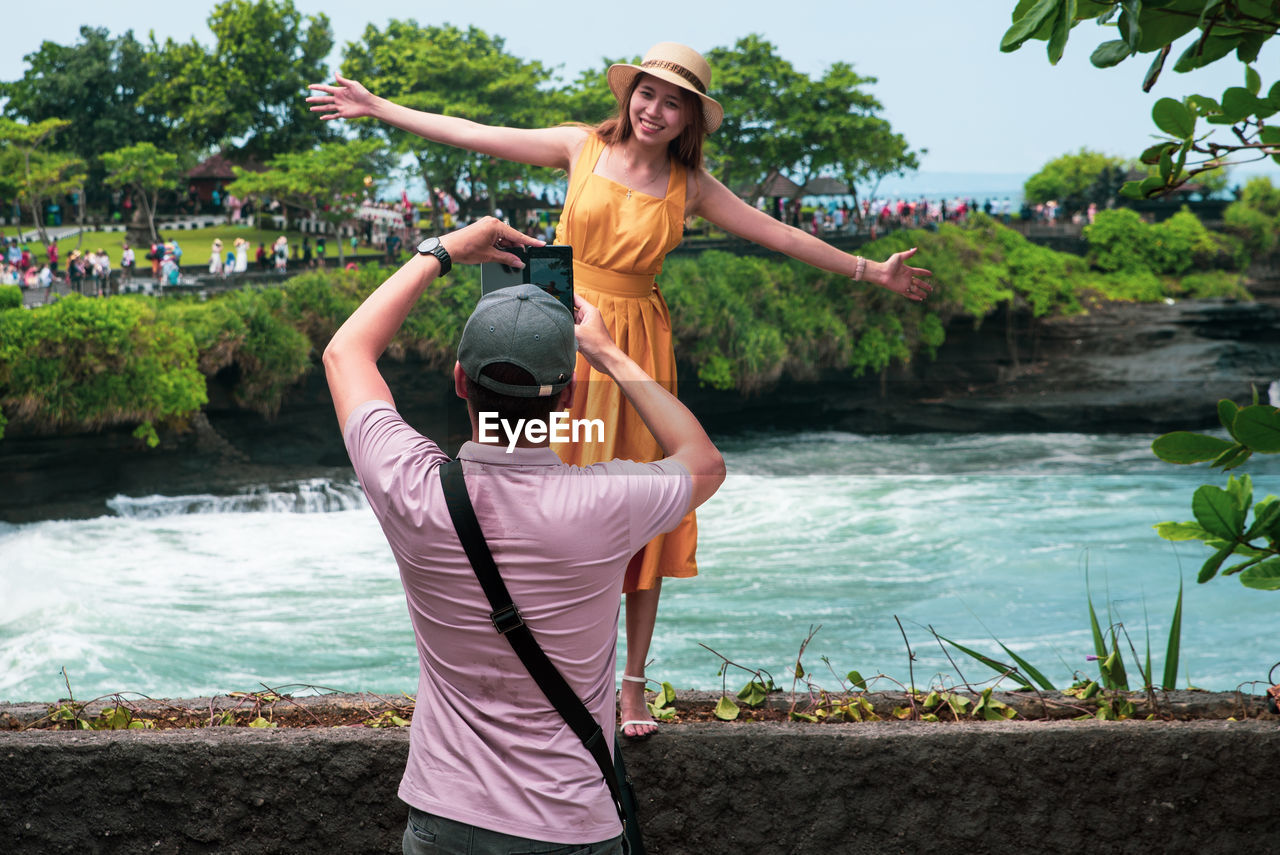 YOUNG WOMAN STANDING BY RIVER