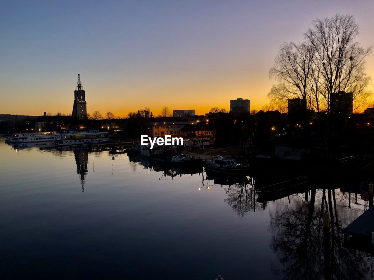 BUILDINGS BY RIVER AGAINST SKY DURING SUNSET