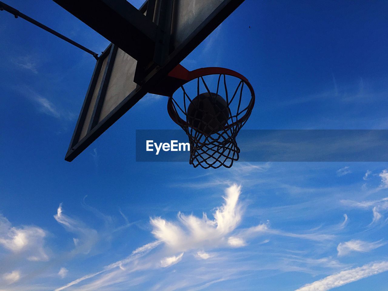 Low angle view of basketball in hoop against blue sky