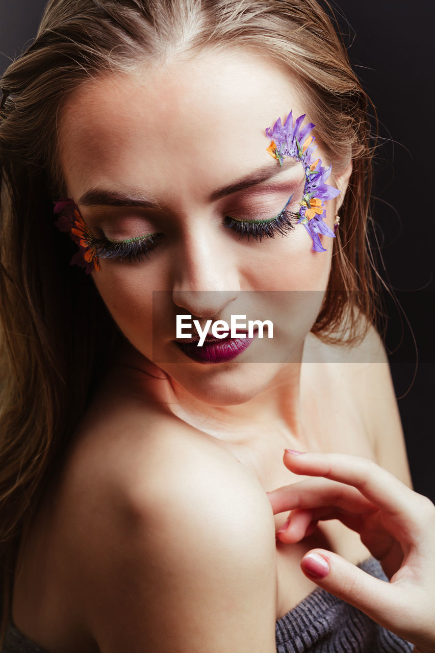 Close-up of beautiful young woman against black background