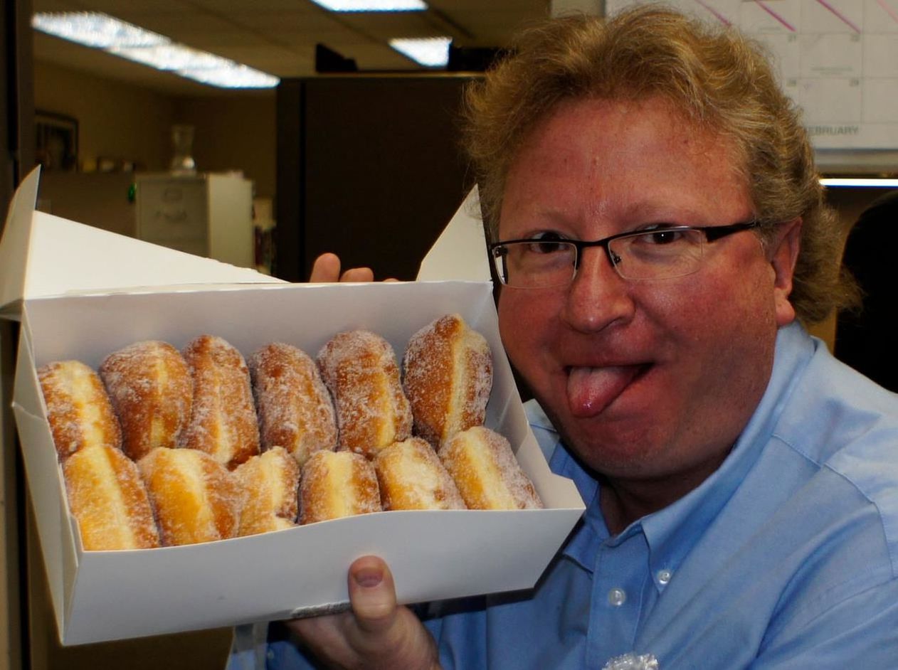 Portrait of man sticking out tongue while holding sweet food in box