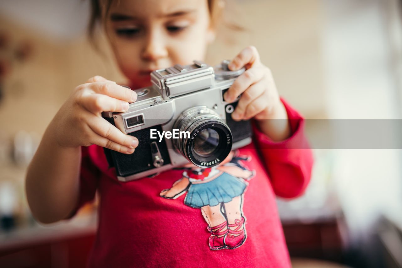 Little girl holding and setting analog camera.