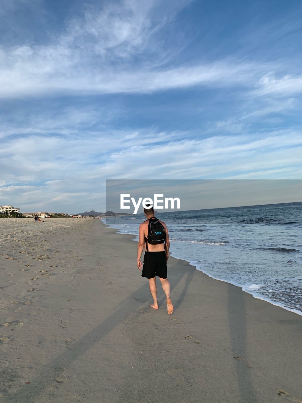 WOMAN STANDING ON BEACH AGAINST SEA