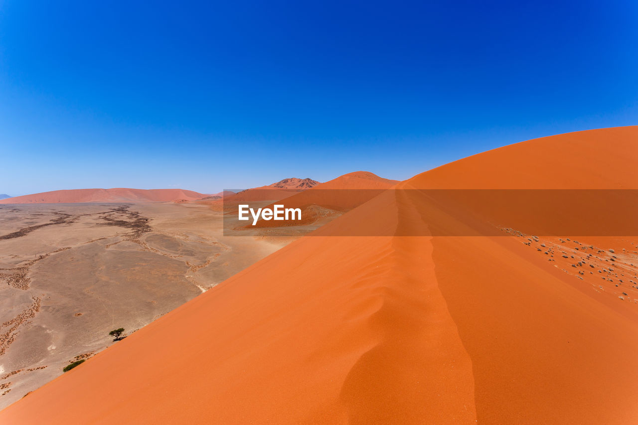 Scenic view of desert against clear blue sky