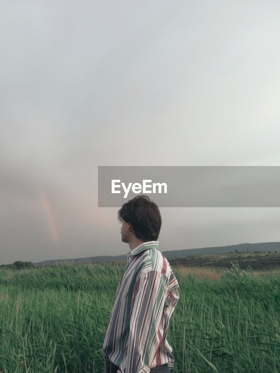 REAR VIEW OF WOMAN LOOKING AT FIELD