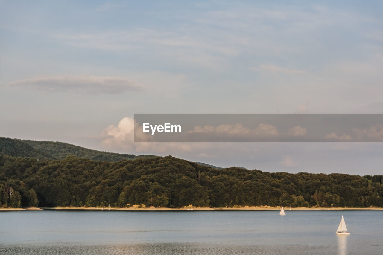 SCENIC VIEW OF LAKE AND MOUNTAINS AGAINST CLOUDY SKY