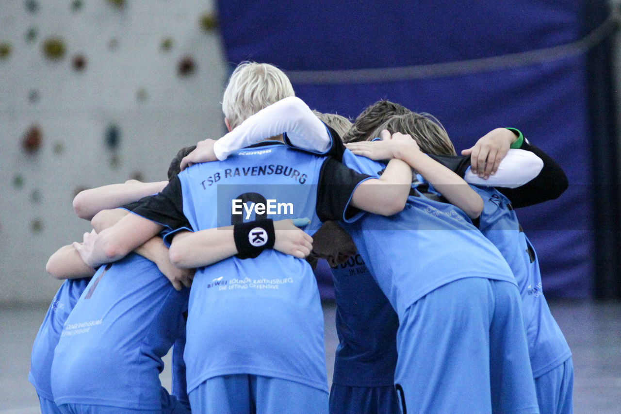 REAR VIEW OF FRIENDS STANDING AGAINST THE BLUE WALL