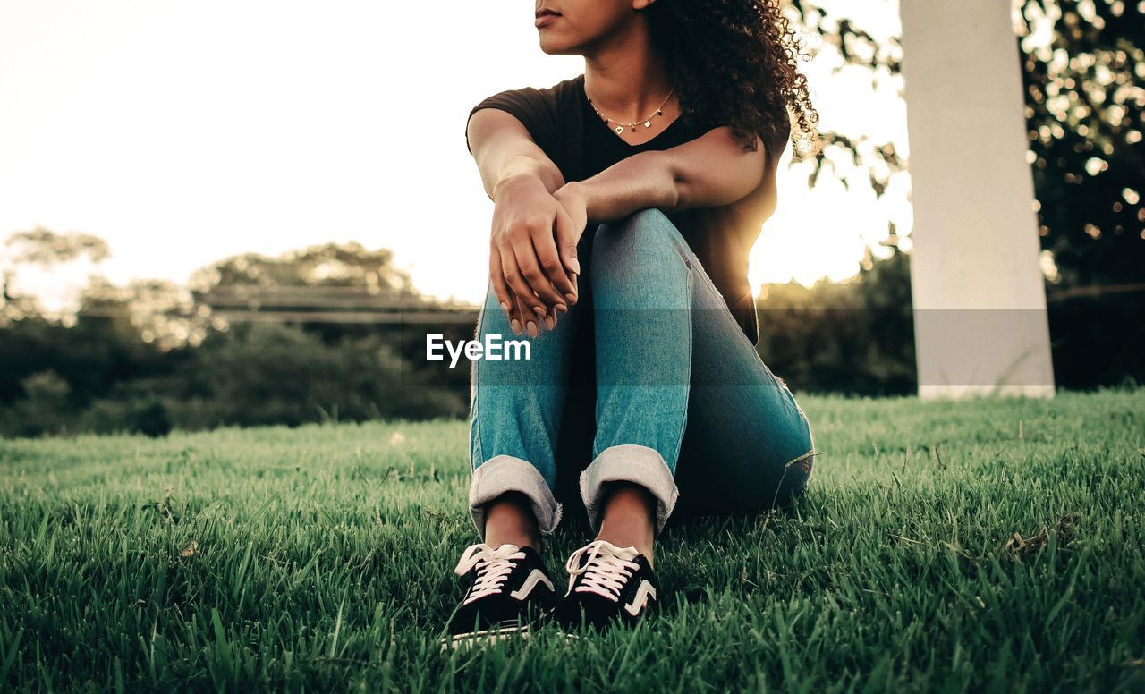 YOUNG WOMAN SITTING ON FIELD