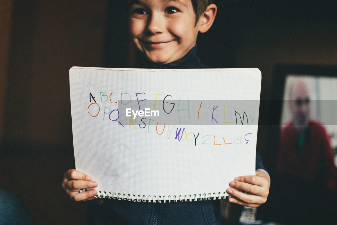Cute little boy smiling while holding alphabet book