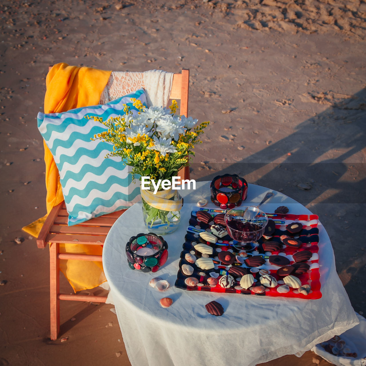 High angle view of chocolates and bracelets on table by chair at beach