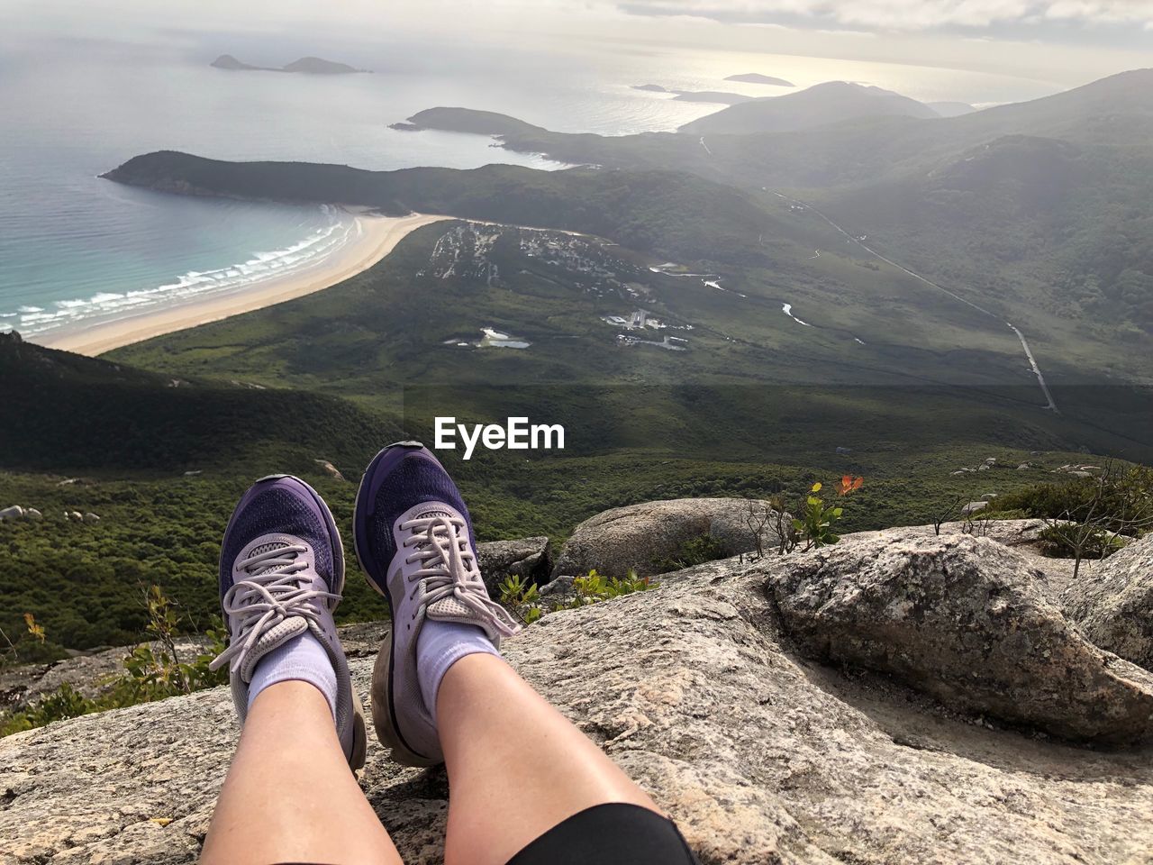 Low section of woman relaxing on cliff 