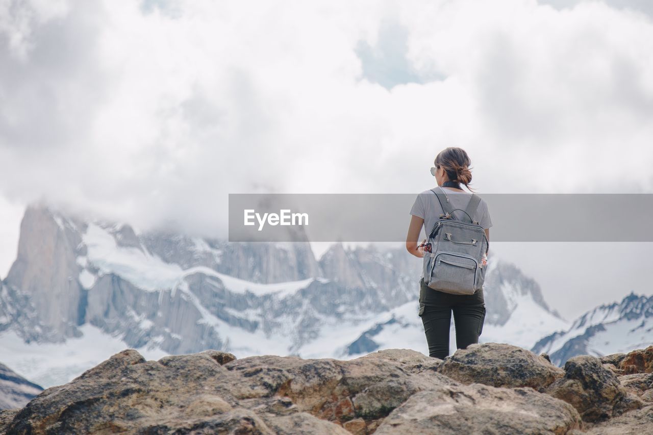 Rear view of woman standing on snowcapped mountain