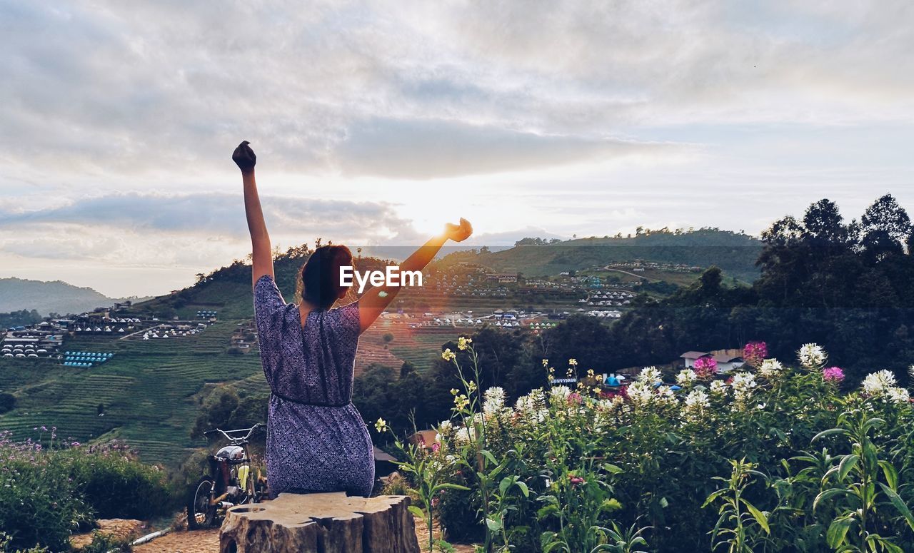 Rear view of women with flowers on mountain against sky