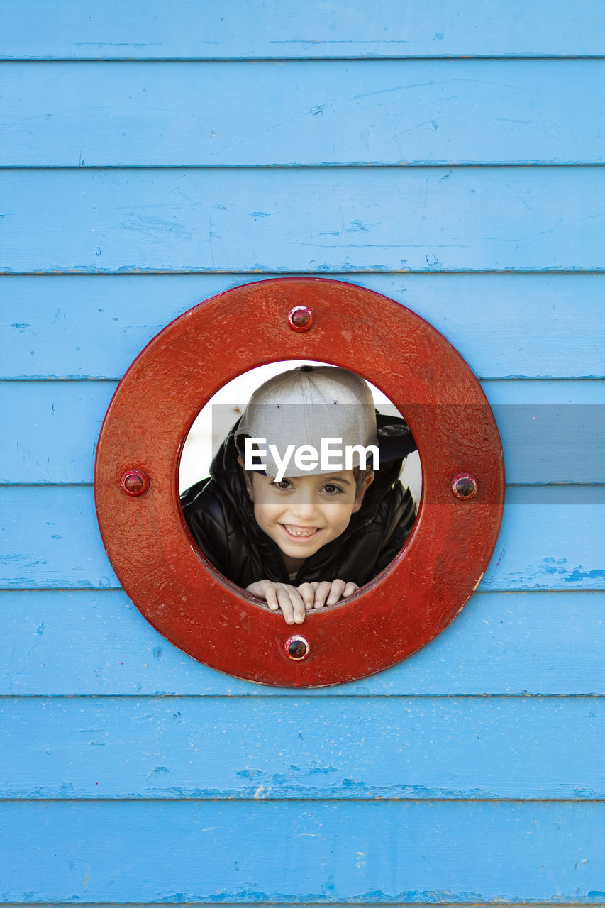 Portrait of smiling boy looking through circle shaped window