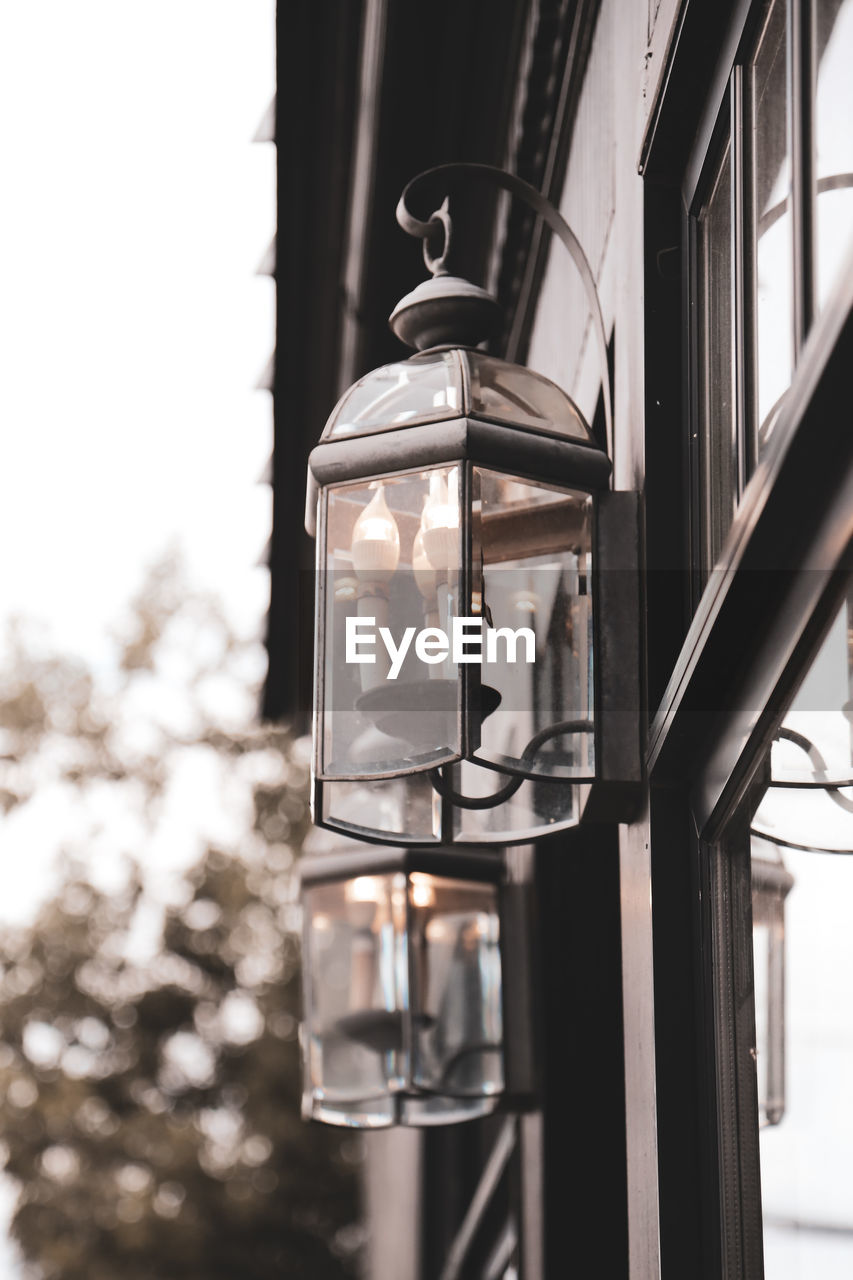 Low angle view of illuminated lighting equipment hanging against building