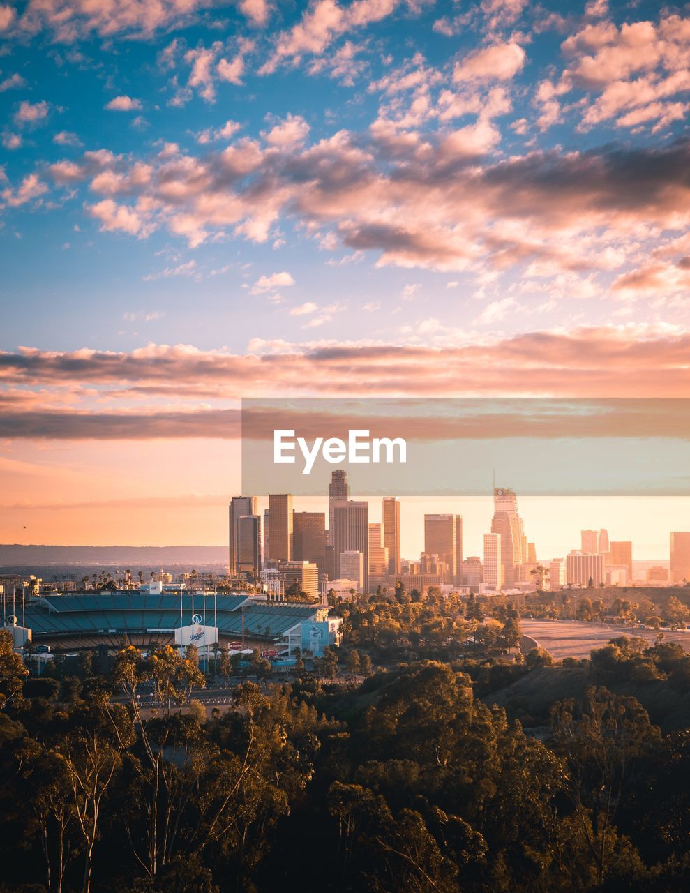 Modern buildings in city against sky during sunset