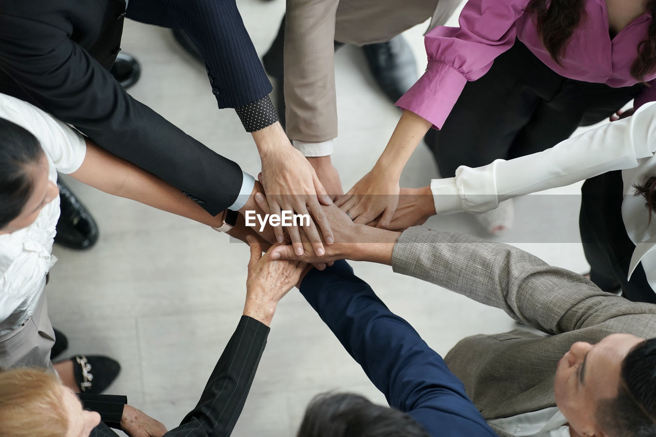 low section of friends stacking hands at workshop