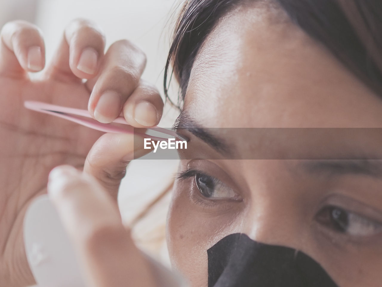 Close-up of woman removing eyebrows