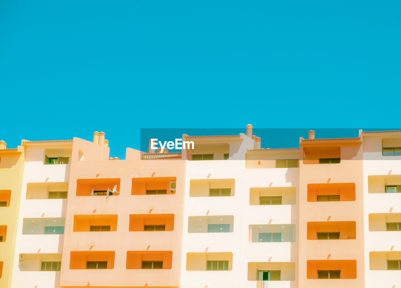 LOW ANGLE VIEW OF RESIDENTIAL BUILDING AGAINST BLUE SKY