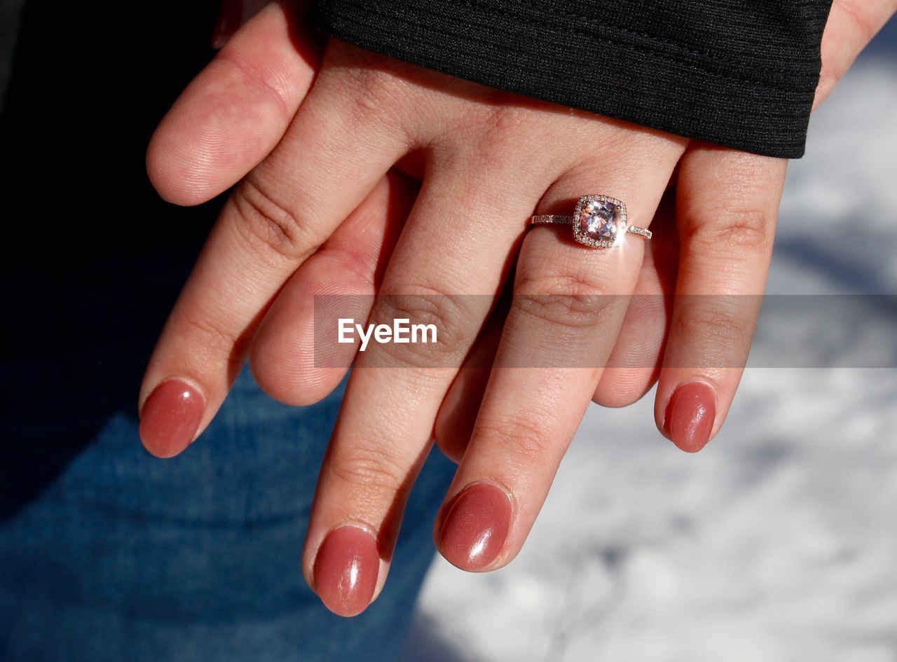 Cropped hand of man holding hands with girlfriend wearing diamond ring