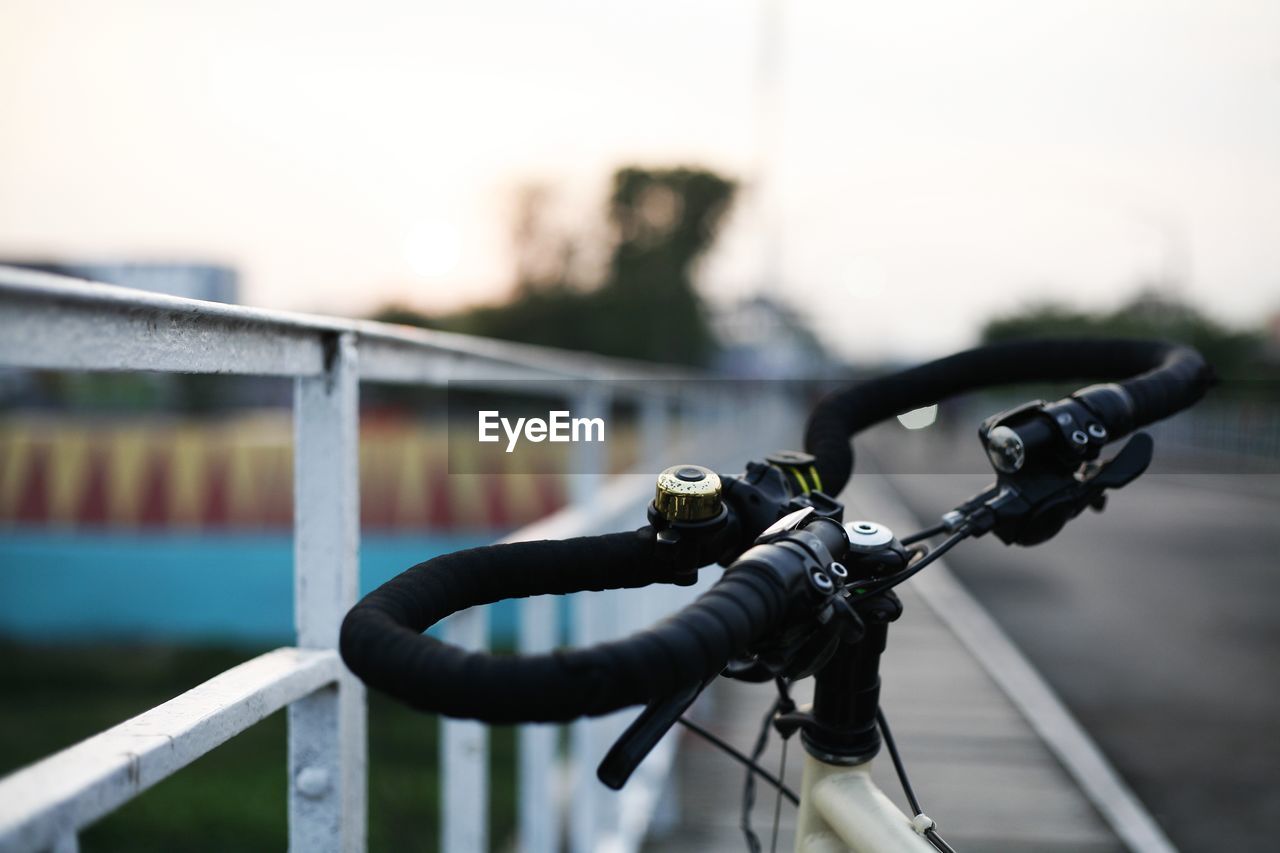 Close-up of bicycle on railing against sky