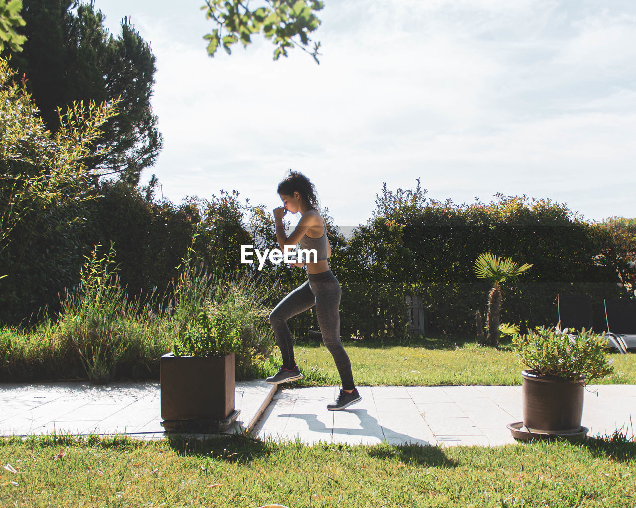 Young woman exercising in her home garden