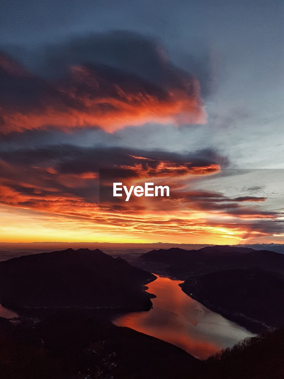 Scenic view of dramatic sky over silhouette mountains during sunset