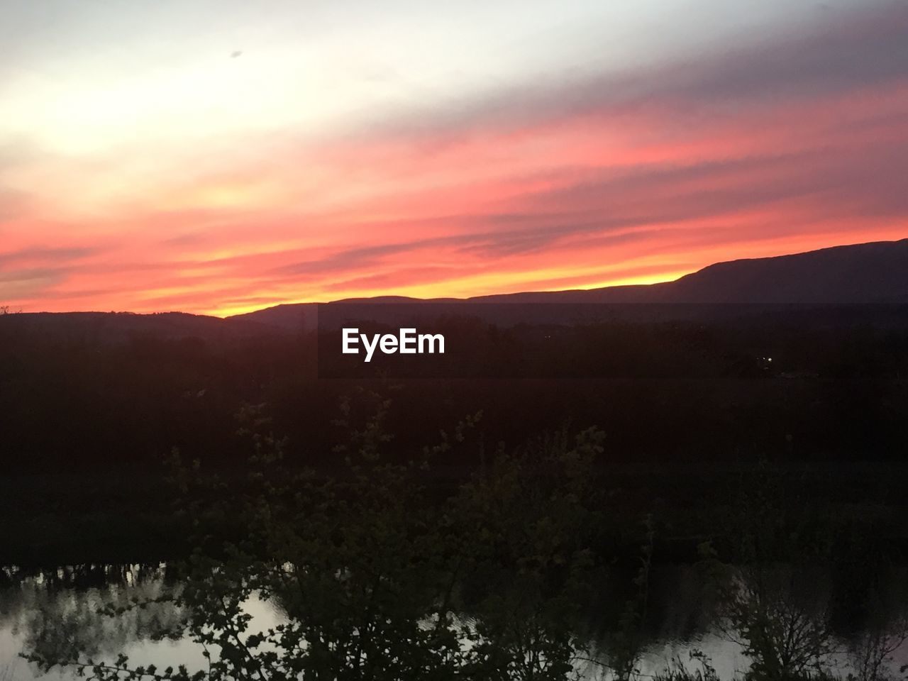 SCENIC VIEW OF SILHOUETTE MOUNTAIN AGAINST ORANGE SKY