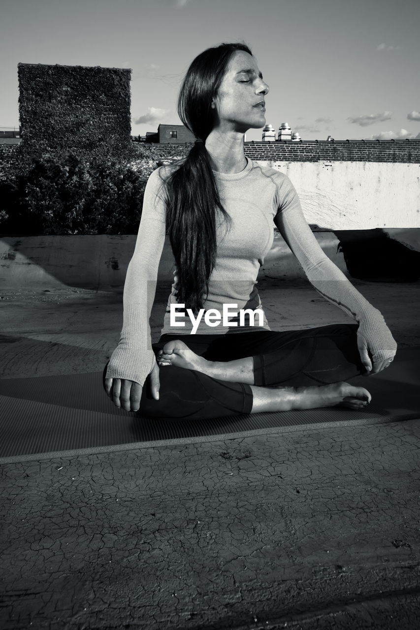 Full length of young woman doing yoga on street