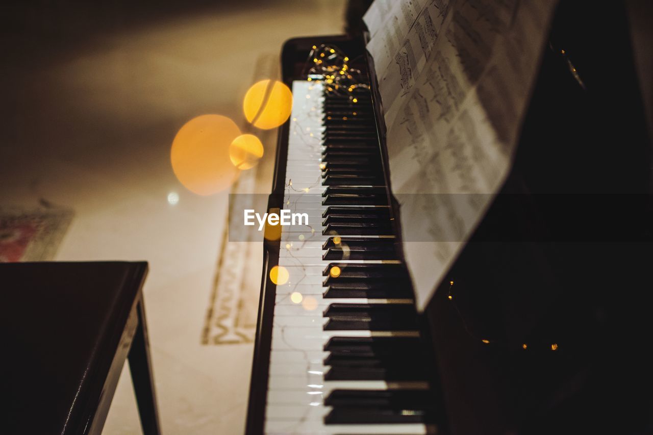 High angle view of illuminated string lights over piano at home