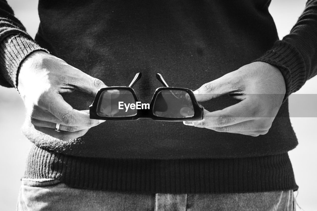 black, black and white, white, monochrome photography, adult, monochrome, midsection, glasses, one person, eyewear, hand, fashion accessory, fashion, clothing, sunglasses, men, close-up, women, indoors, holding, front view, goggles, lifestyles, belt, standing, vision care, casual clothing