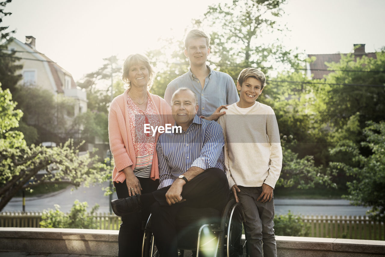 Portrait of happy disabled man with family at yard