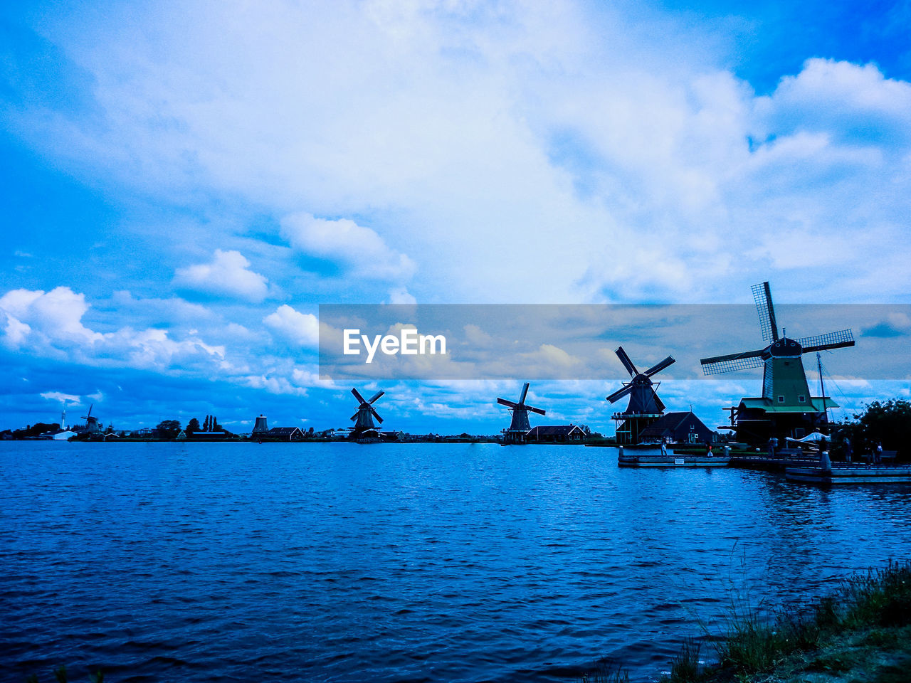 Traditional windmills by lake against sky at night