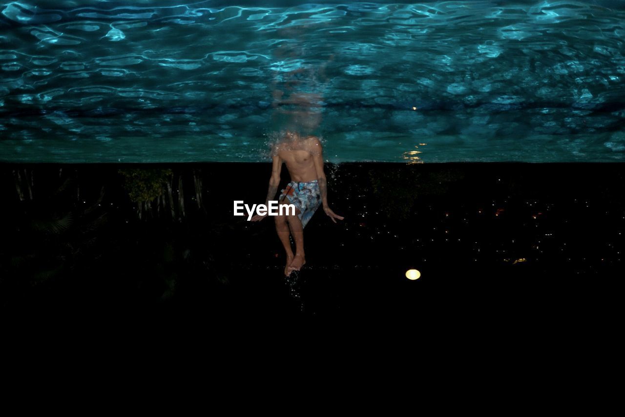 Upside down image of man swimming in water at night