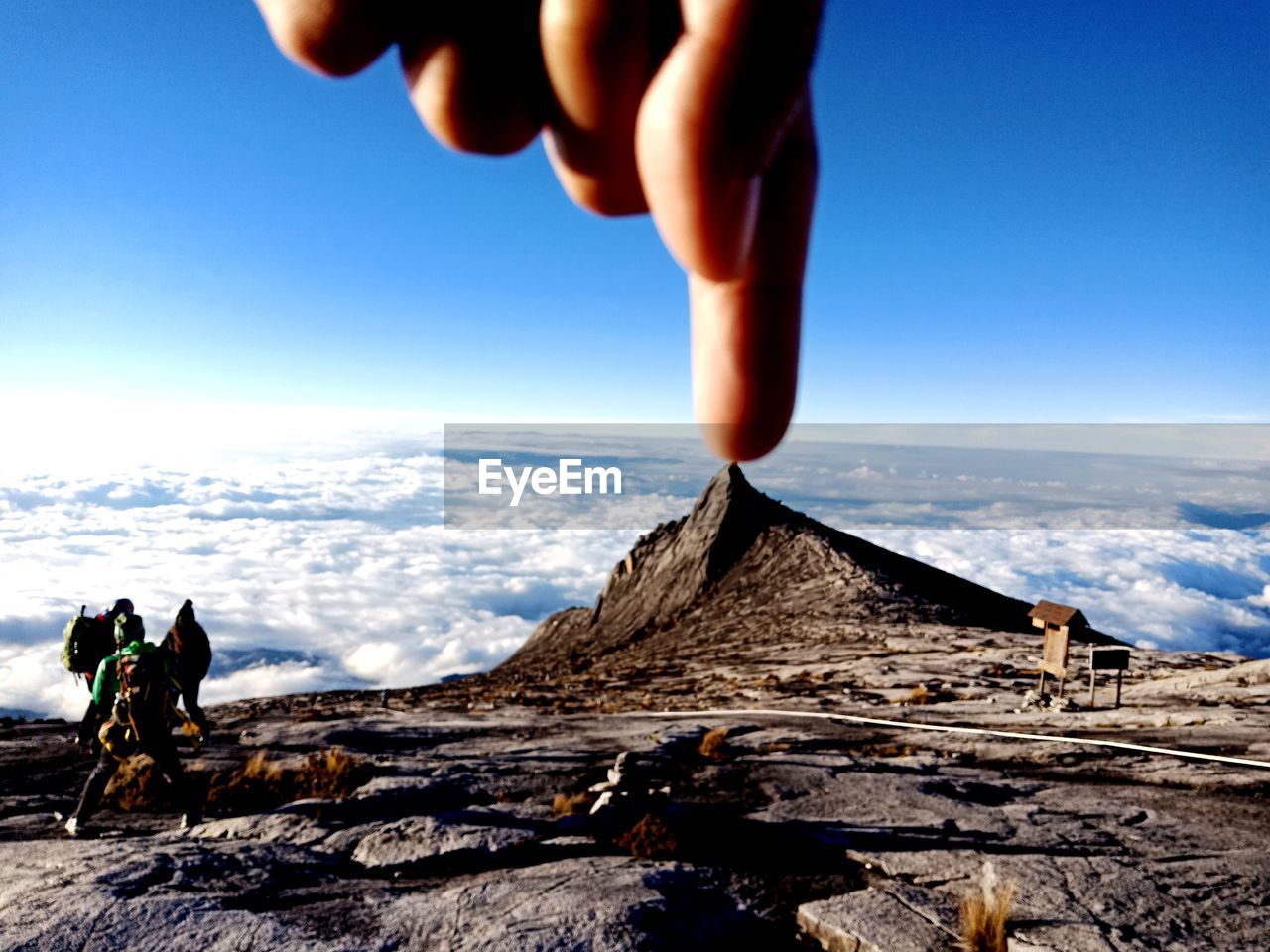 CROPPED IMAGE OF HAND AGAINST MOUNTAIN RANGE