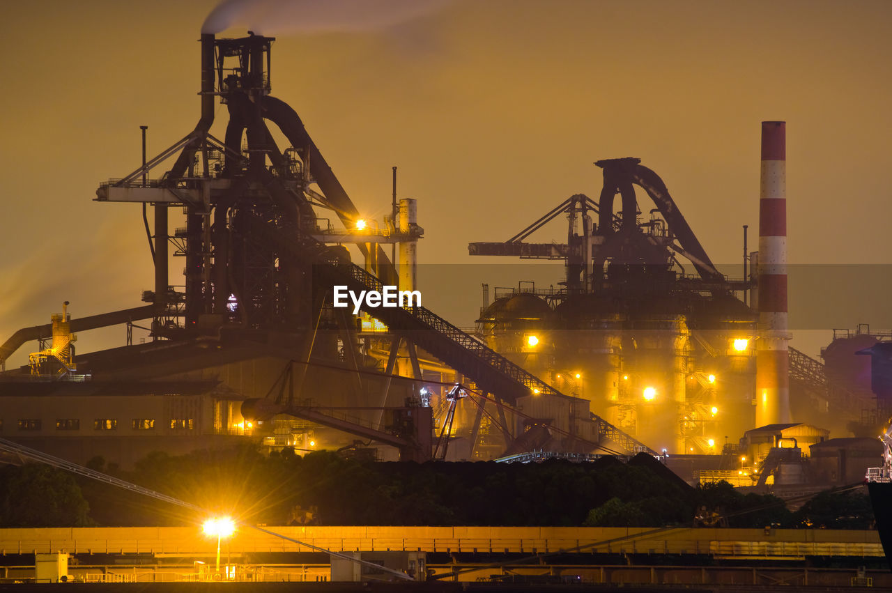 Cranes at commercial dock against sky