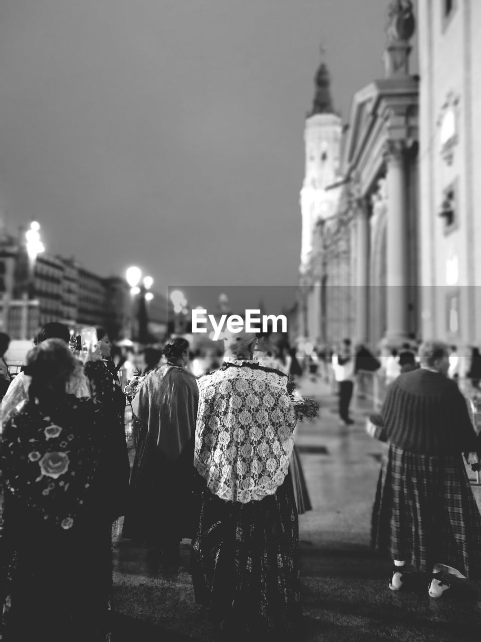 REAR VIEW OF PEOPLE IN FRONT OF TEMPLE AGAINST SKY IN CITY