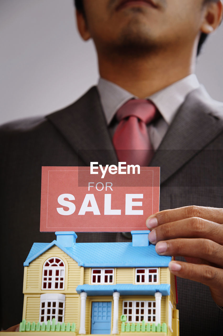 Midsection of businessman with model home and sale message