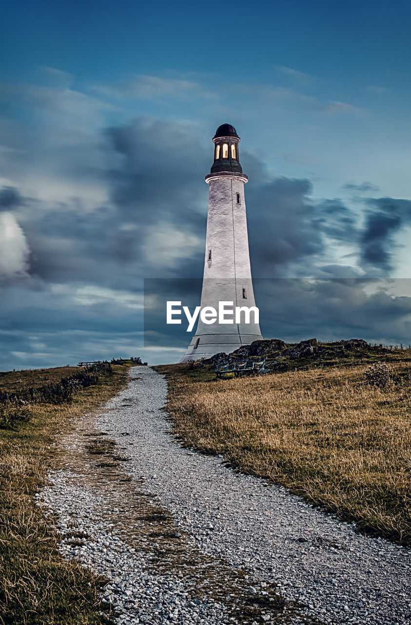 Lighthouse on landscape against sky