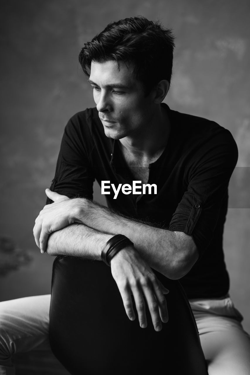 Handsome man looking down while sitting on chair