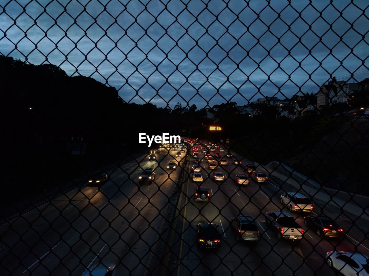 Daily commute in highway as seen from the bridge above through a fence